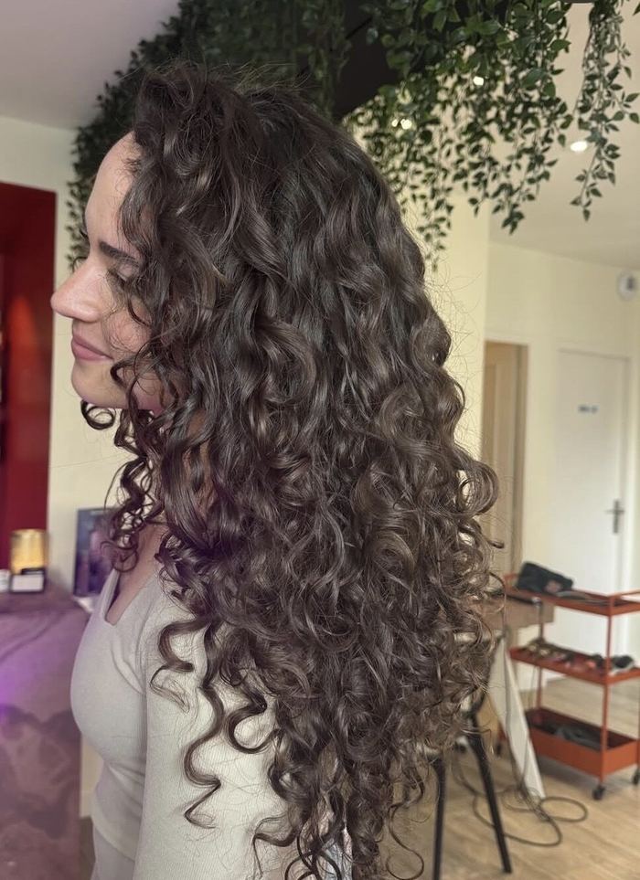 Longues boucles brunes définies, vues de profil dans le salon.