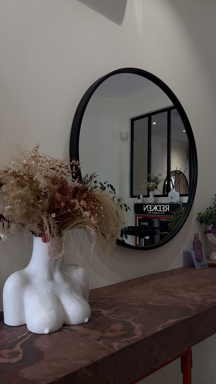 Console en bois, miroir rond et bouquet séché dans l'espace d'accueil.